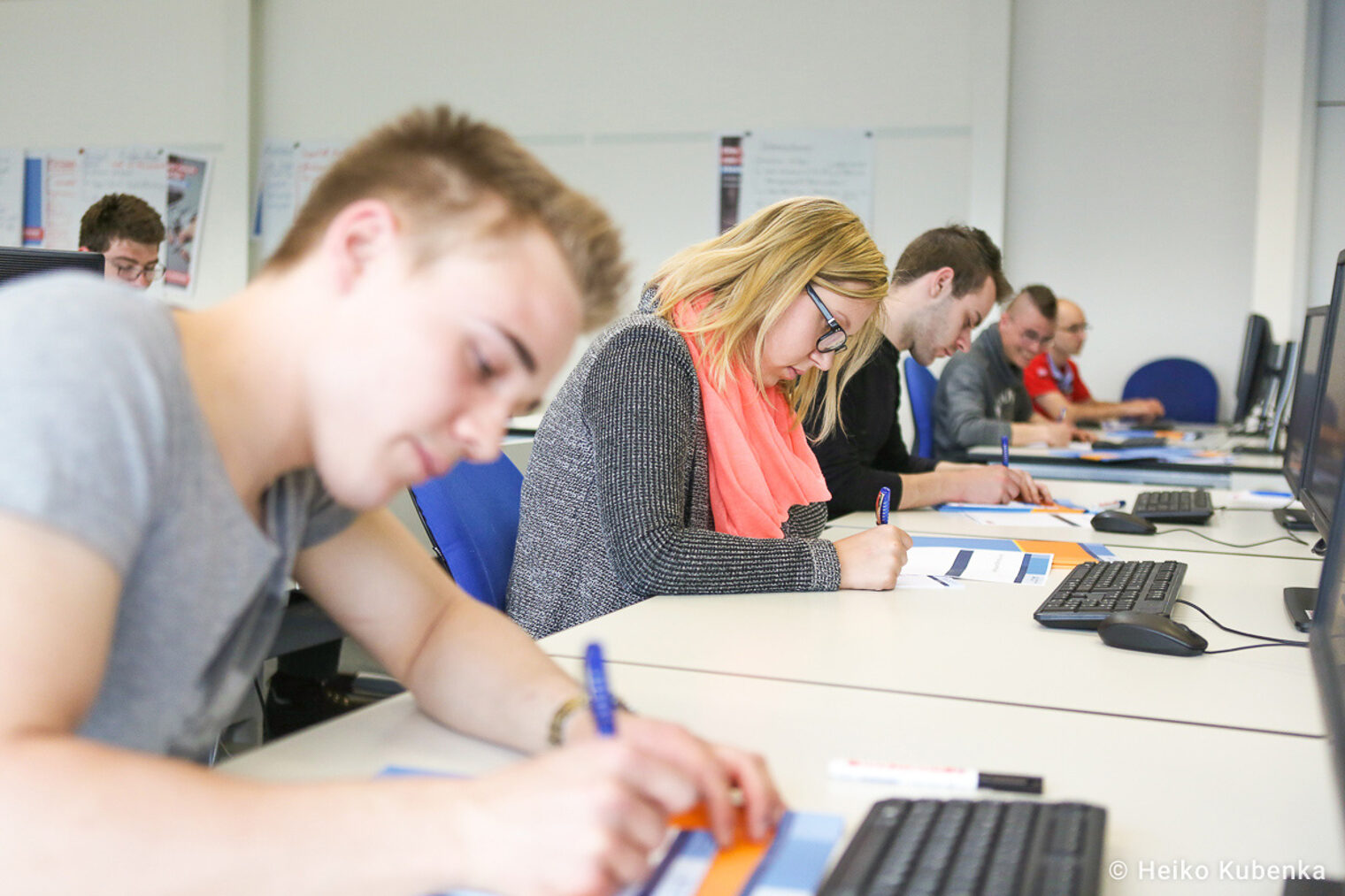 Seminarteilnehmer Seminarteilnehmer sitzt vor einem Computer und schreibt etwas auf ein Blatt Papier.